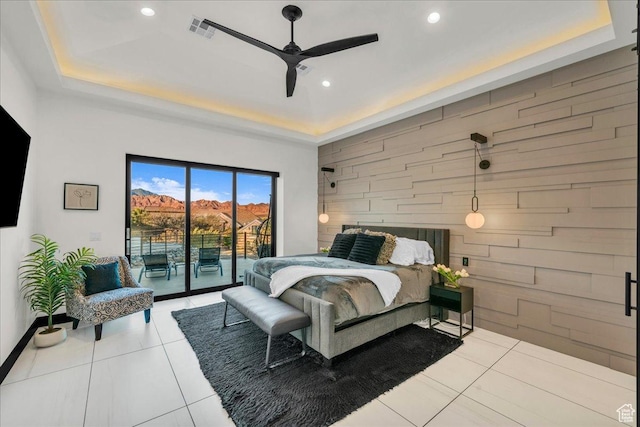 bedroom with ceiling fan, access to exterior, a raised ceiling, and light tile patterned floors