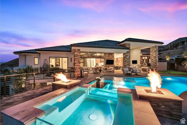 pool at dusk with an outdoor living space with a fireplace and a patio area
