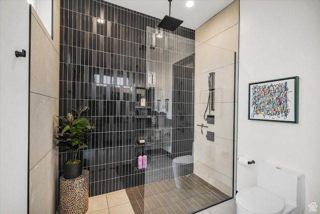bathroom with tile patterned floors, toilet, and tiled shower