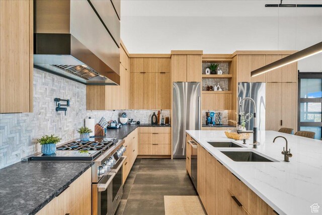 kitchen featuring sink, wall chimney range hood, stainless steel appliances, light stone countertops, and backsplash