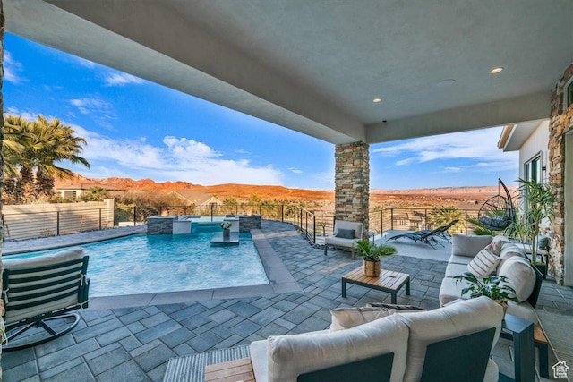view of pool featuring pool water feature, an outdoor living space, a mountain view, and a patio area