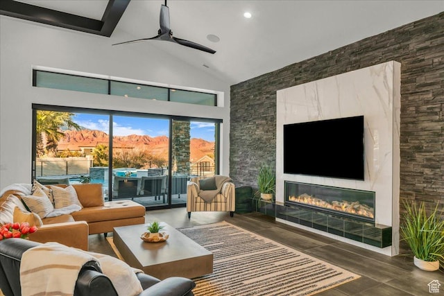 living room featuring beamed ceiling, ceiling fan, a fireplace, and high vaulted ceiling