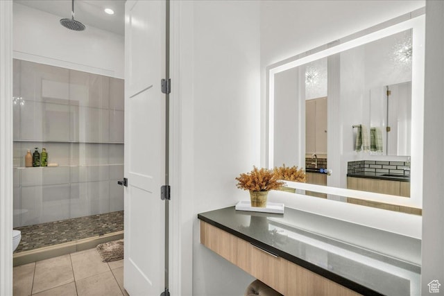 bathroom featuring tile patterned floors, toilet, vanity, and a shower