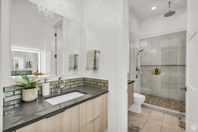 bathroom with tile patterned flooring, vanity, a tile shower, and toilet