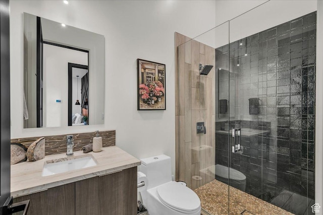 bathroom featuring a shower with door, vanity, and toilet