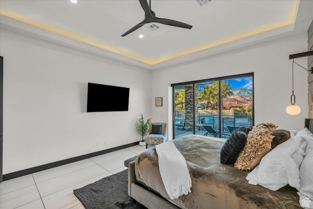 tiled bedroom featuring ceiling fan, a raised ceiling, and access to outside
