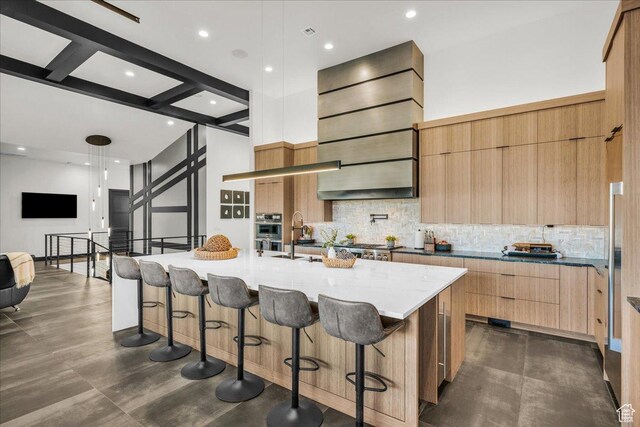 kitchen featuring a large island, backsplash, beam ceiling, and decorative light fixtures