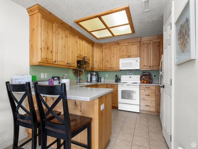 11085 S Grape Arbor Pl Unit 102, Sandy, UT 84070 - kitchen with a kitchen breakfast bar, light tile patterned floors, white appliances, kitchen peninsula, and a textured ceiling