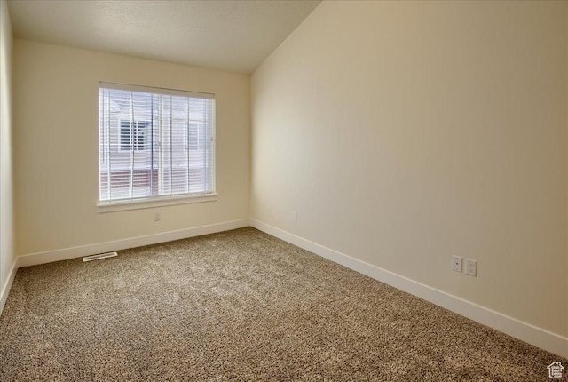 unfurnished room featuring lofted ceiling and carpet flooring