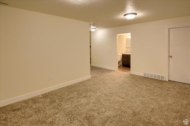 carpeted empty room with a textured ceiling