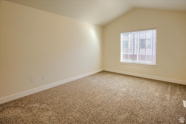 carpeted empty room featuring vaulted ceiling