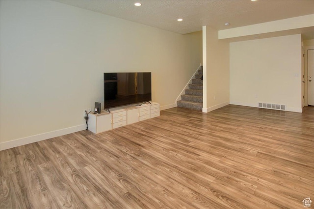 unfurnished living room featuring light hardwood / wood-style floors and a textured ceiling