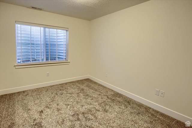 carpeted empty room with a textured ceiling