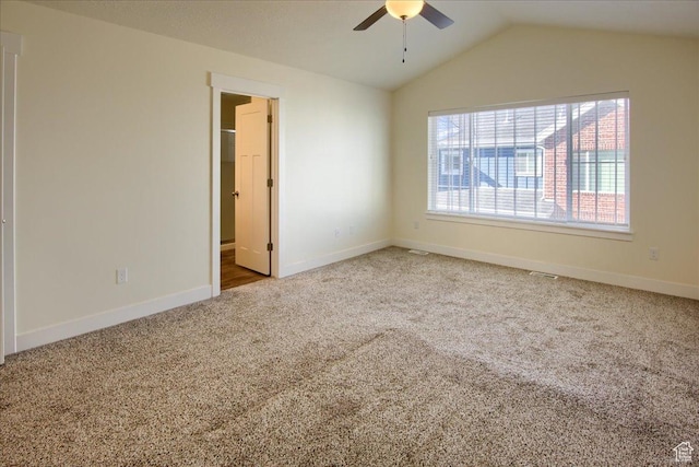 empty room featuring lofted ceiling, light colored carpet, and ceiling fan