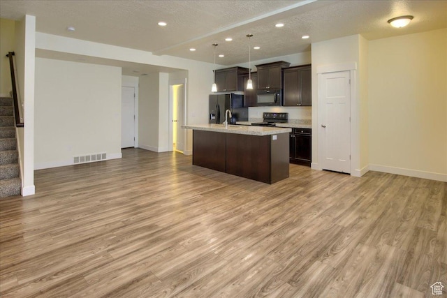 kitchen with dark brown cabinetry, light wood-type flooring, black appliances, and a center island with sink
