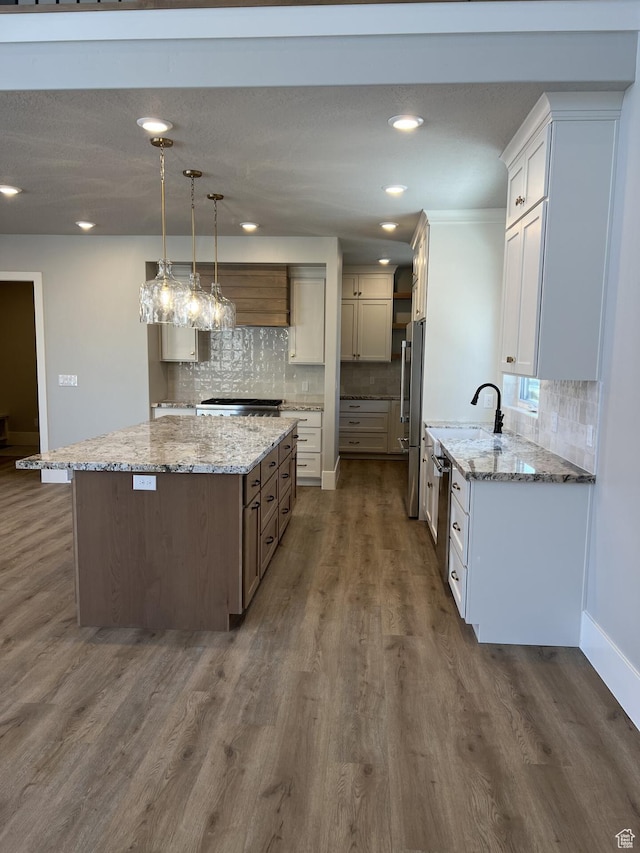 kitchen featuring pendant lighting, dark wood-type flooring, appliances with stainless steel finishes, light stone countertops, and a kitchen island