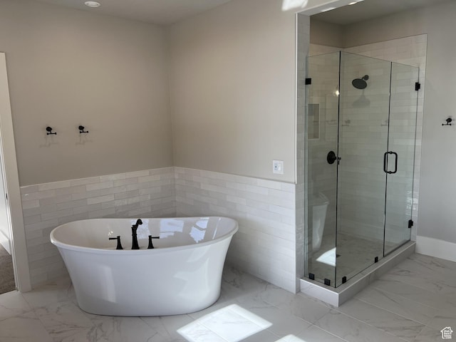 bathroom with tile walls and separate shower and tub