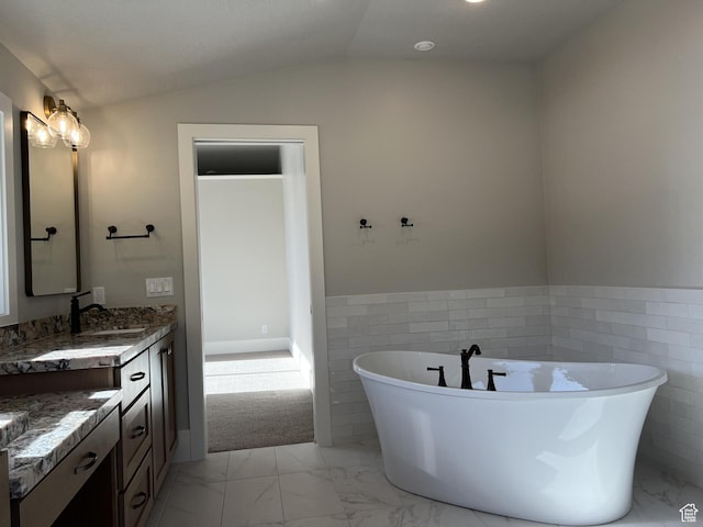 bathroom with lofted ceiling, vanity, a bath, and tile walls