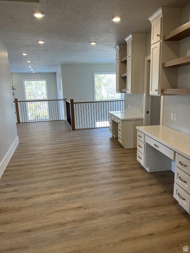 kitchen with white cabinetry, built in desk, a textured ceiling, and dark hardwood / wood-style flooring