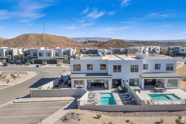 rear view of house with a mountain view, a patio, and a fenced in pool
