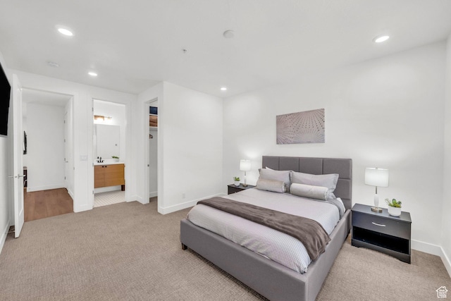 bedroom with ensuite bathroom and light colored carpet