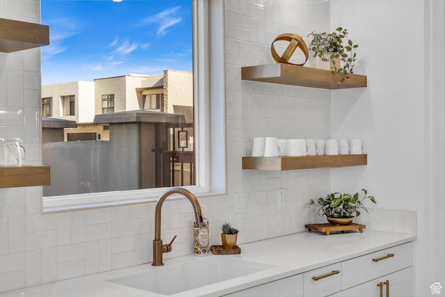 kitchen featuring white cabinetry, sink, and tasteful backsplash