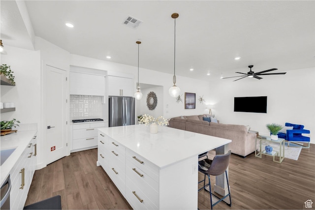 kitchen with dark wood-type flooring, a kitchen island, white cabinets, and appliances with stainless steel finishes