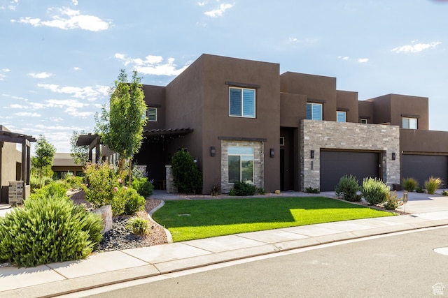 pueblo-style home featuring a garage and a front lawn