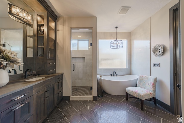 bathroom featuring an inviting chandelier, vanity, and plus walk in shower