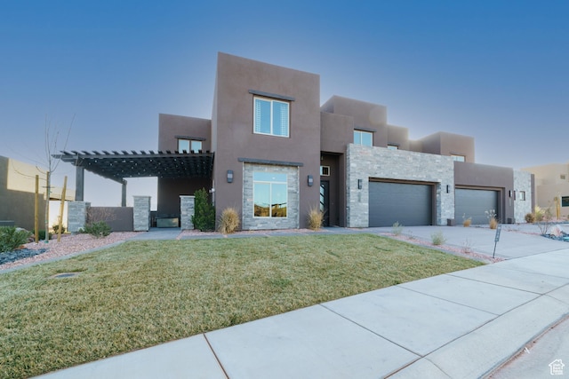 pueblo-style home featuring a garage and a front lawn