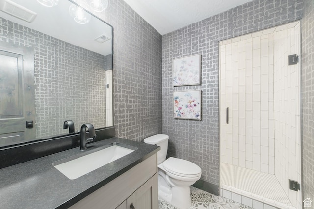 bathroom with tile walls, vanity, toilet, and a tile shower
