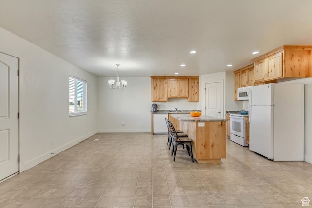 kitchen featuring a kitchen bar, decorative light fixtures, light brown cabinets, a kitchen island, and white appliances