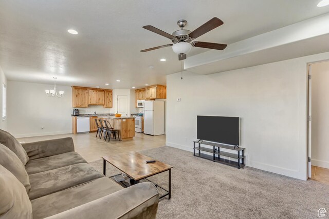 carpeted living room featuring ceiling fan with notable chandelier