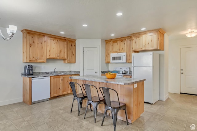 kitchen featuring sink, white appliances, a kitchen breakfast bar, a kitchen island, and light brown cabinets