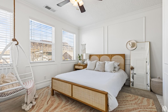 carpeted bedroom featuring crown molding, visible vents, and ceiling fan