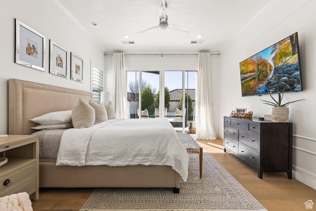 bedroom with wood finished floors, access to outside, visible vents, and ceiling fan