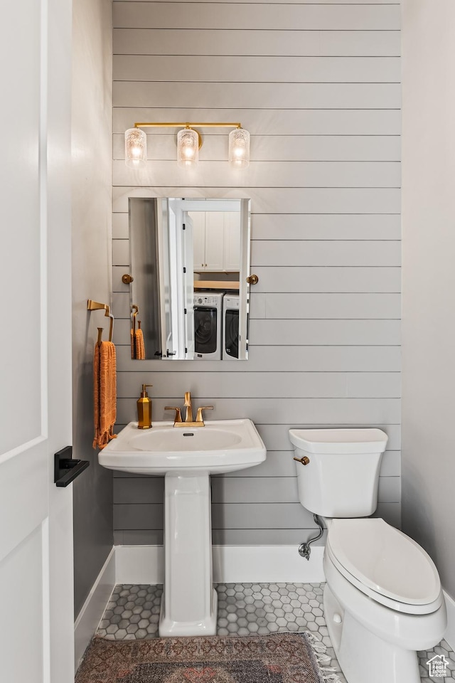 bathroom featuring toilet, independent washer and dryer, tile patterned flooring, and wooden walls