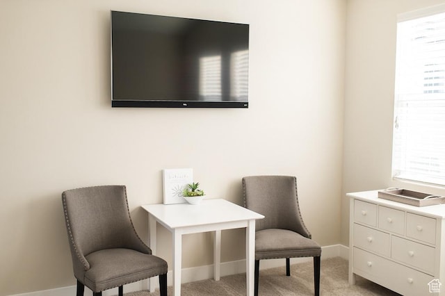 living area with baseboards and light colored carpet