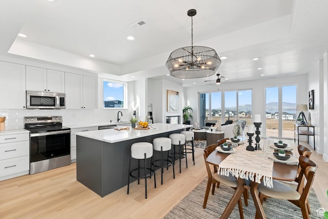 113 E Watson Dr S, Saratoga Springs, UT 84045 - kitchen with decorative light fixtures, light wood-type flooring, a kitchen island, stainless steel appliances, and white cabinets