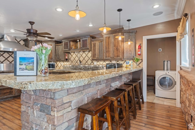 75 N 200 W, Kanab, UT 84741 - kitchen featuring a kitchen bar, washer / dryer, light stone counters, hanging light fixtures, and kitchen peninsula