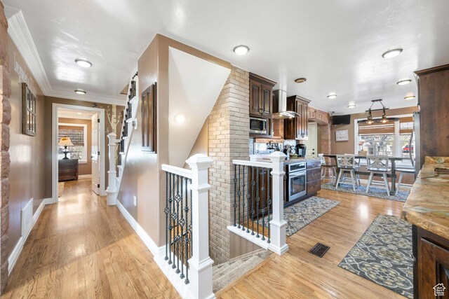 75 N 200 W, Kanab, UT 84741 - kitchen featuring pendant lighting, stainless steel appliances, dark brown cabinetry, light hardwood / wood-style floors, and wall chimney exhaust hood