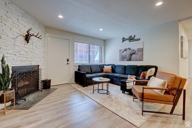 407 S Vasels Rd Unit 8, Brian Head, UT 84719 - living room with a stone fireplace, light hardwood / wood-style flooring, and a textured ceiling