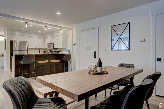 dining area with light hardwood / wood-style floors, sink, and a textured ceiling