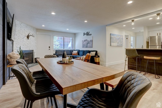 407 S Vasels Rd Unit 8, Brian Head, UT 84719 - dining space with a stone fireplace, light hardwood / wood-style flooring, and a textured ceiling