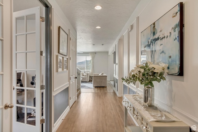 739 W Wild Hyacinth Dr, Saratoga Springs, UT 84045 - hall featuring light wood-type flooring, a textured ceiling, and french doors
