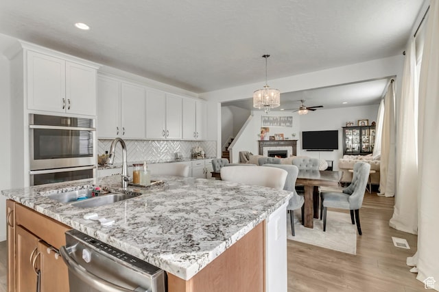 739 W Wild Hyacinth Dr, Saratoga Springs, UT 84045 - kitchen with appliances with stainless steel finishes, white cabinetry, sink, a kitchen island with sink, and light stone counters