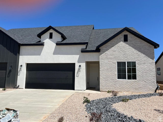 344 W Rosie Loop Unit 46E, Cedar City, UT 84721 - view of front of home featuring stone siding, a garage, driveway, roof with shingles, and stucco siding