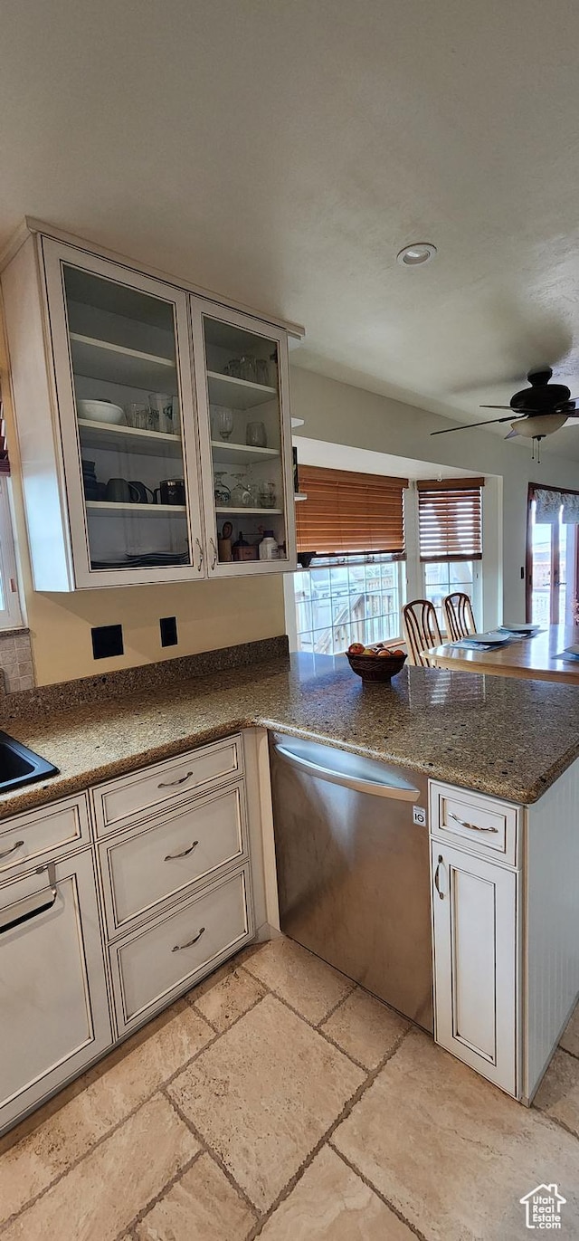 kitchen with sink, stainless steel dishwasher, ceiling fan, and stone countertops