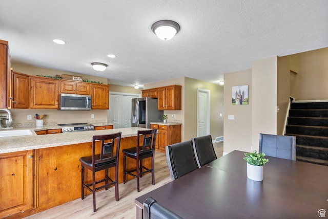 700 S Clearwater Falls Dr E, Layton, UT 84041 - kitchen featuring sink, a breakfast bar area, kitchen peninsula, stainless steel appliances, and light wood-type flooring