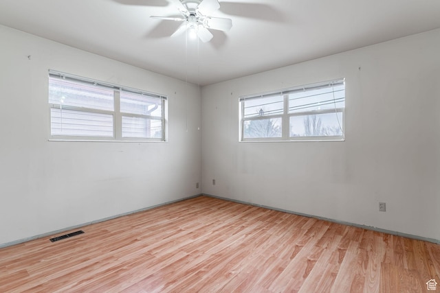 empty room with ceiling fan, a wealth of natural light, and light wood-type flooring